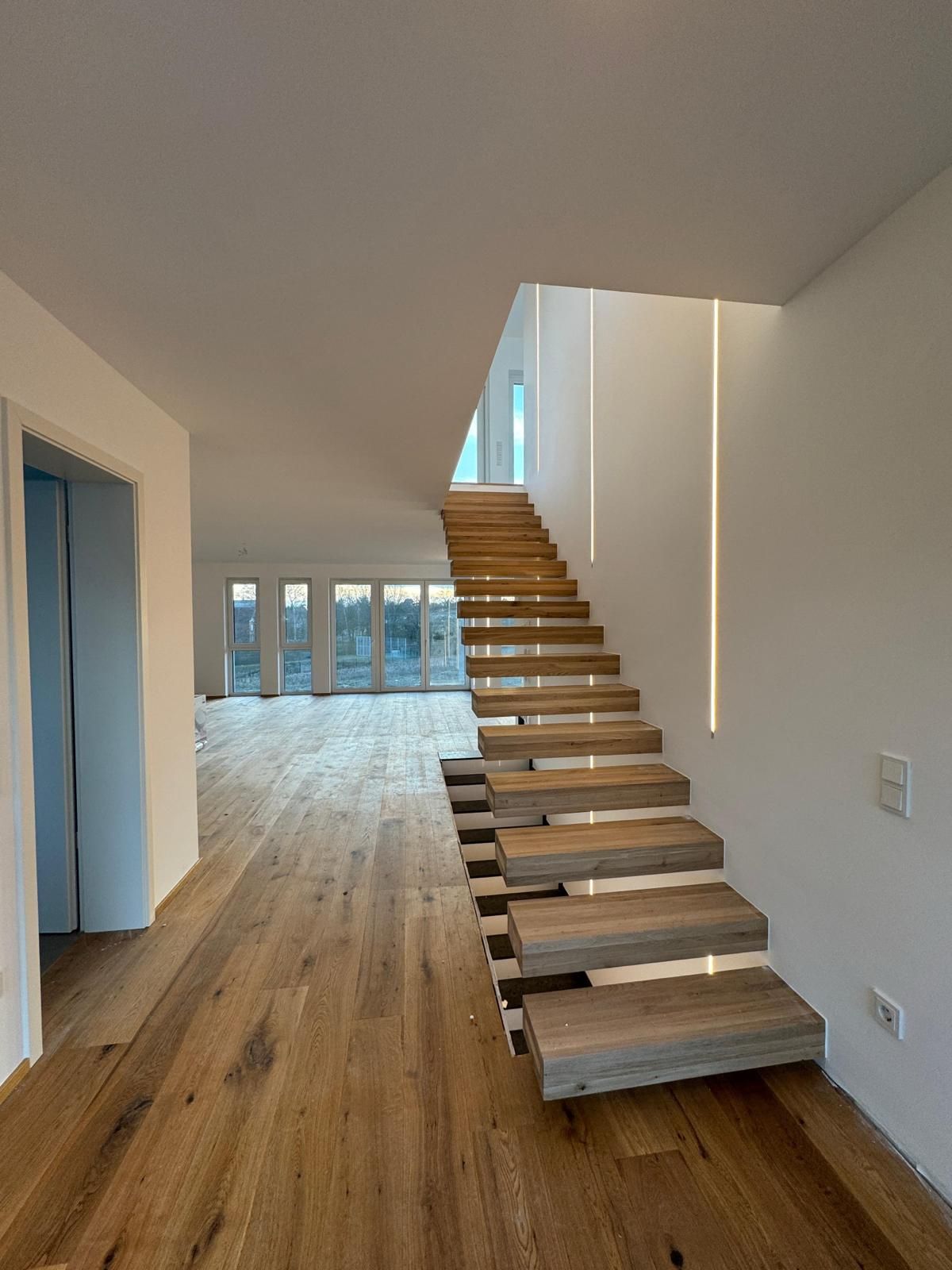 Freitragende Holztreppe mit LED-Lichtlinie in der Wand